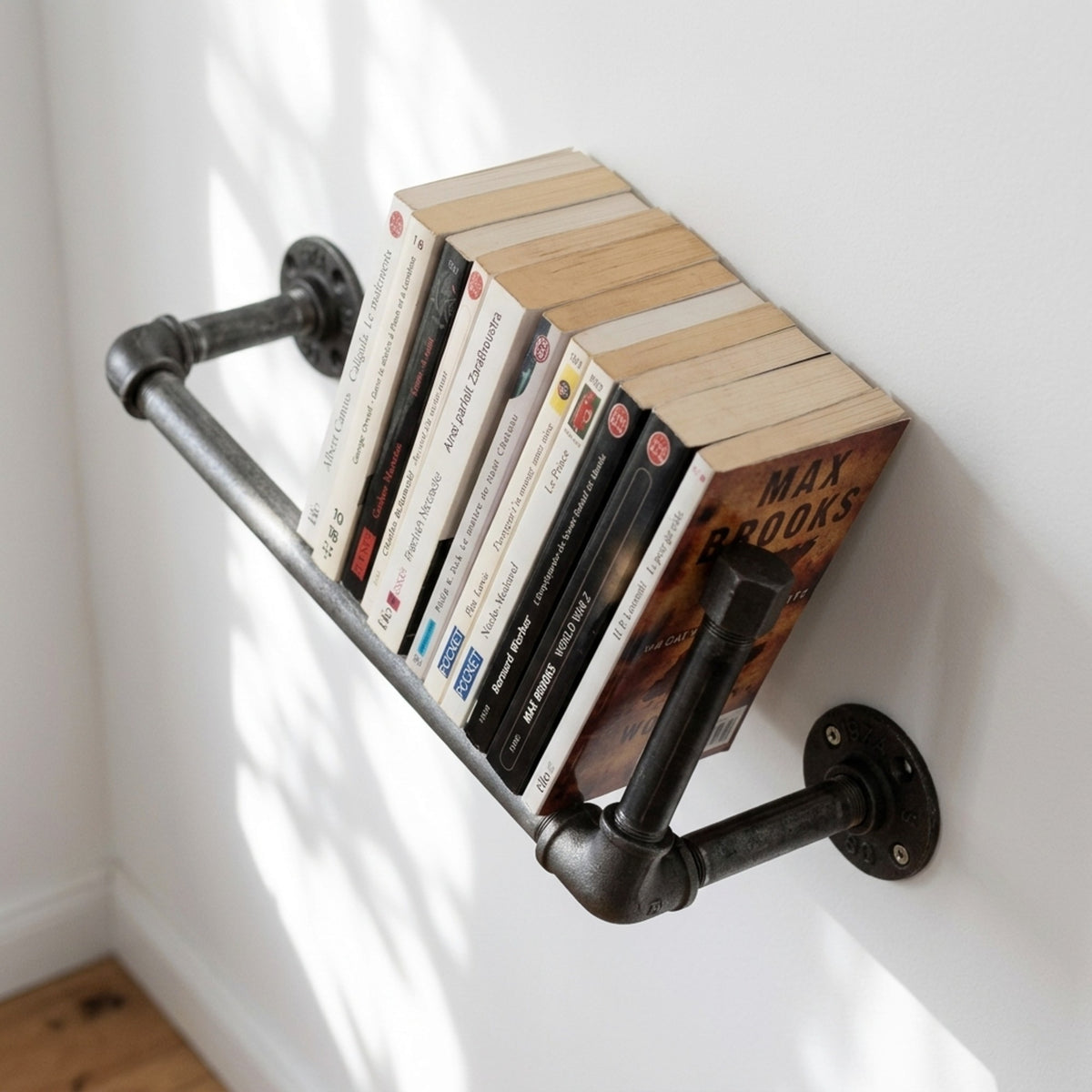 Wandregal aus Temperguss an heller Wand mit Taschenbüchern, Raumansicht