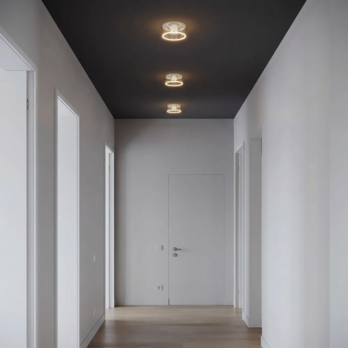 Drei LED-Donut-Lampen E27 aus klarem Glas nebeneinander an der Decke eines reduzierten Flurs