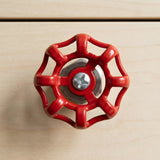 Bouton de meuble volant rouge en inox sur meuble en bois