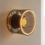 LED-Donut-Lampe E27 aus Rauchglas, Ø 120 mm, eingeschaltet als Wandleuchte an einer neutralen einfarbigen Wand