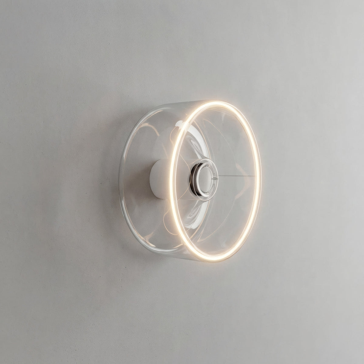 LED-Donut-Lampe E27 aus klarem Glas, Ø 195 mm, eingeschaltet als Wandleuchte in einem reduzierten Interieur