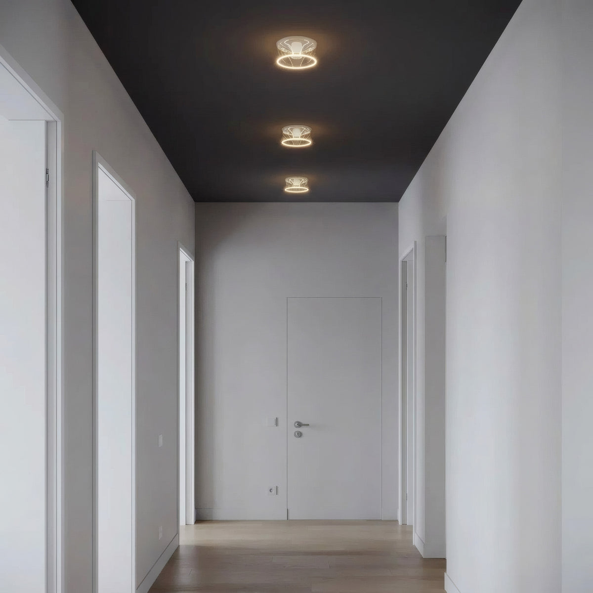 Drei LED-Donut-Lampen E27 aus klarem Glas nebeneinander an der Decke eines reduzierten Flurs