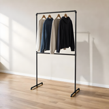 Portant à vêtements autoportant double barre en tuyaux de plomberie noirs Ø 27 mm, vêtements sur cintres en bois dans une pièce claire à parquet chêne